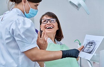 Dentist reviewing X-ray with smiling patient