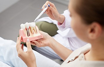 Patient holding sample dental implant that dentist is pointing to