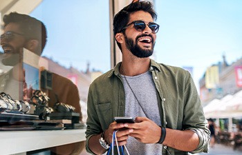 Man with sunglasses smiling while shopping outside