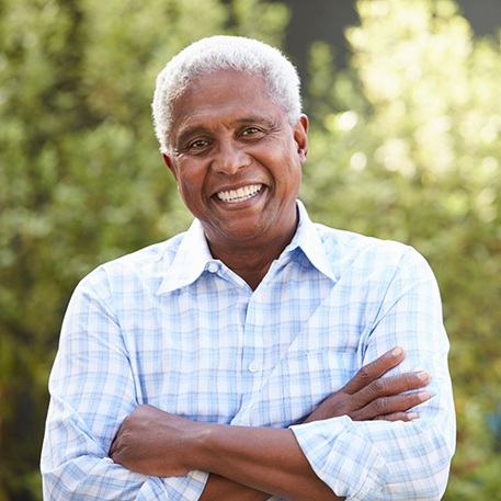 Man outside smiling with arms crossed casually over chest