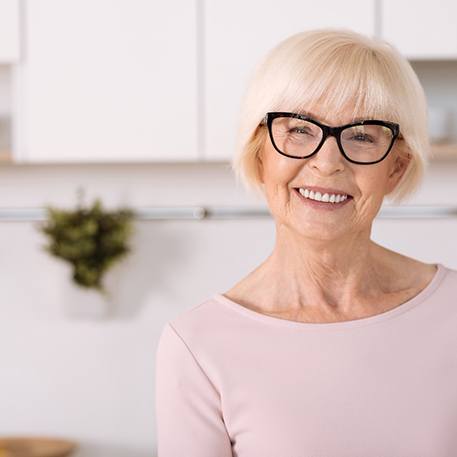 Senior woman standing and smiling in her kitchen