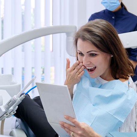 Happy dental patient looking at her smile in the mirror