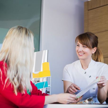 Dental receptionist talking with patient at front desk