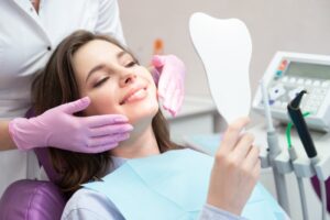 Woman in dentist's chair smiling and looking into a mirror.