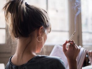 Woman smoking cigarette and reading book.